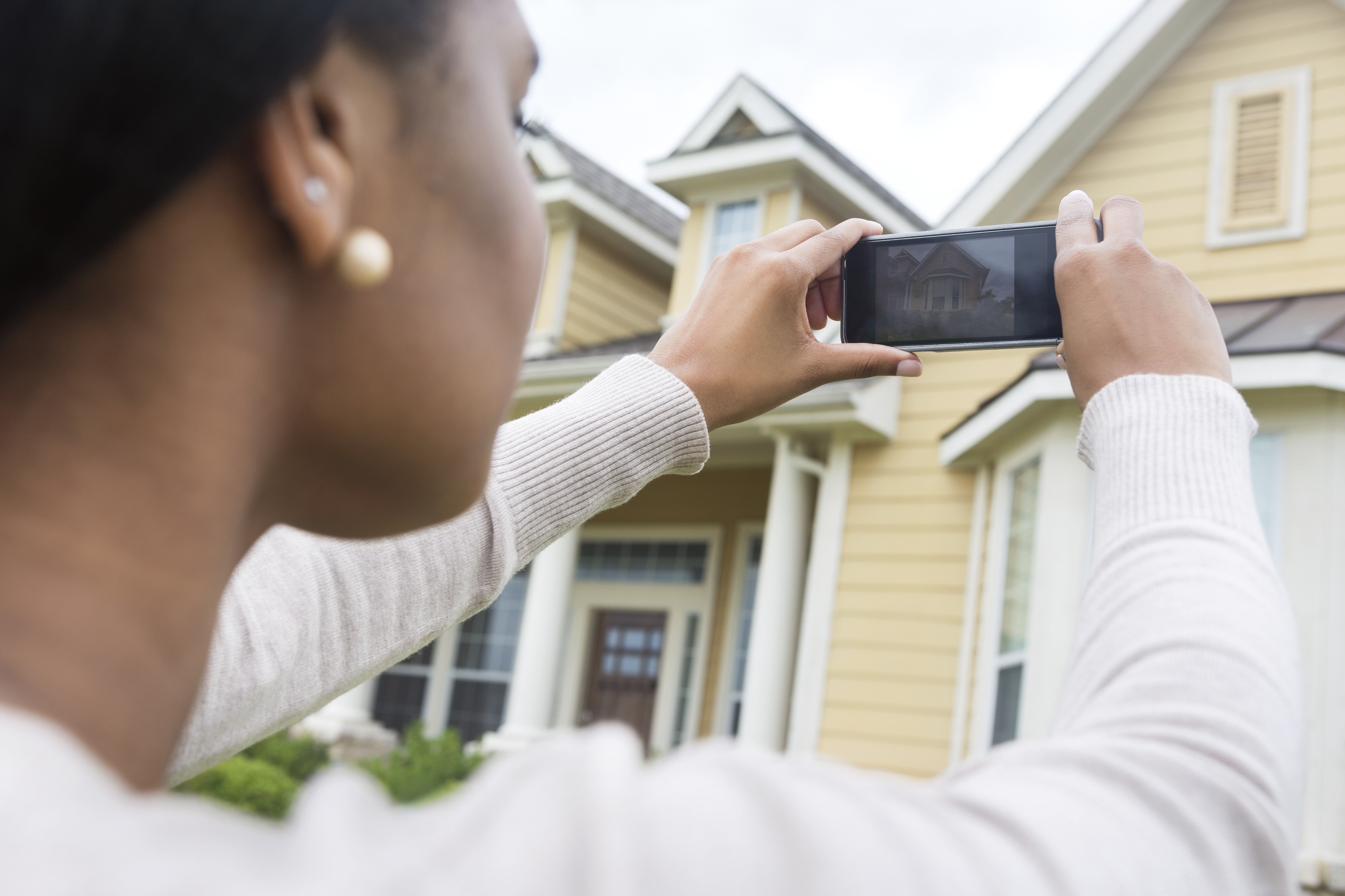 woman taking a photo of a house on the market she wants to buy